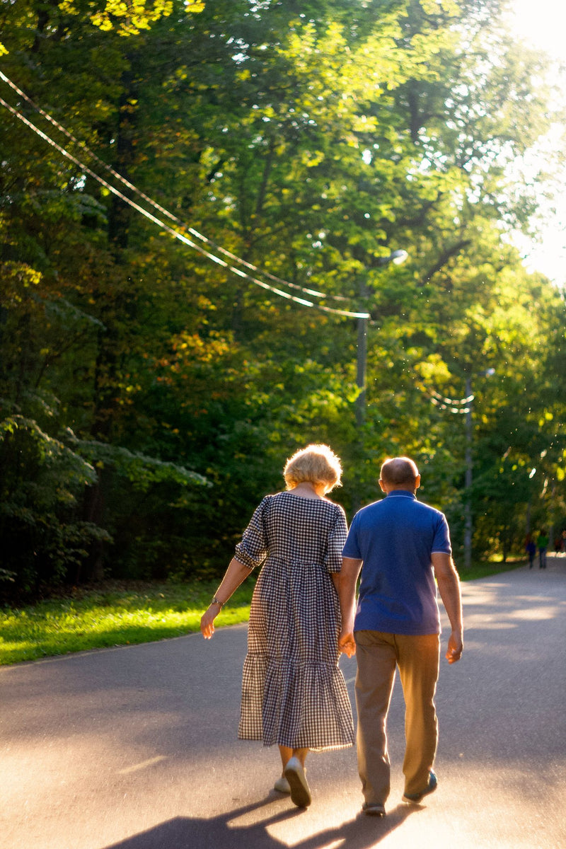 Couple de seniors marchant sur une allée de parc au soleil couchant