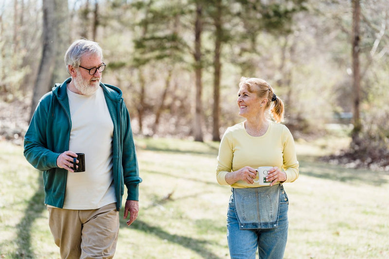 Couple de seniors marchant en extérieur, tasse à la main